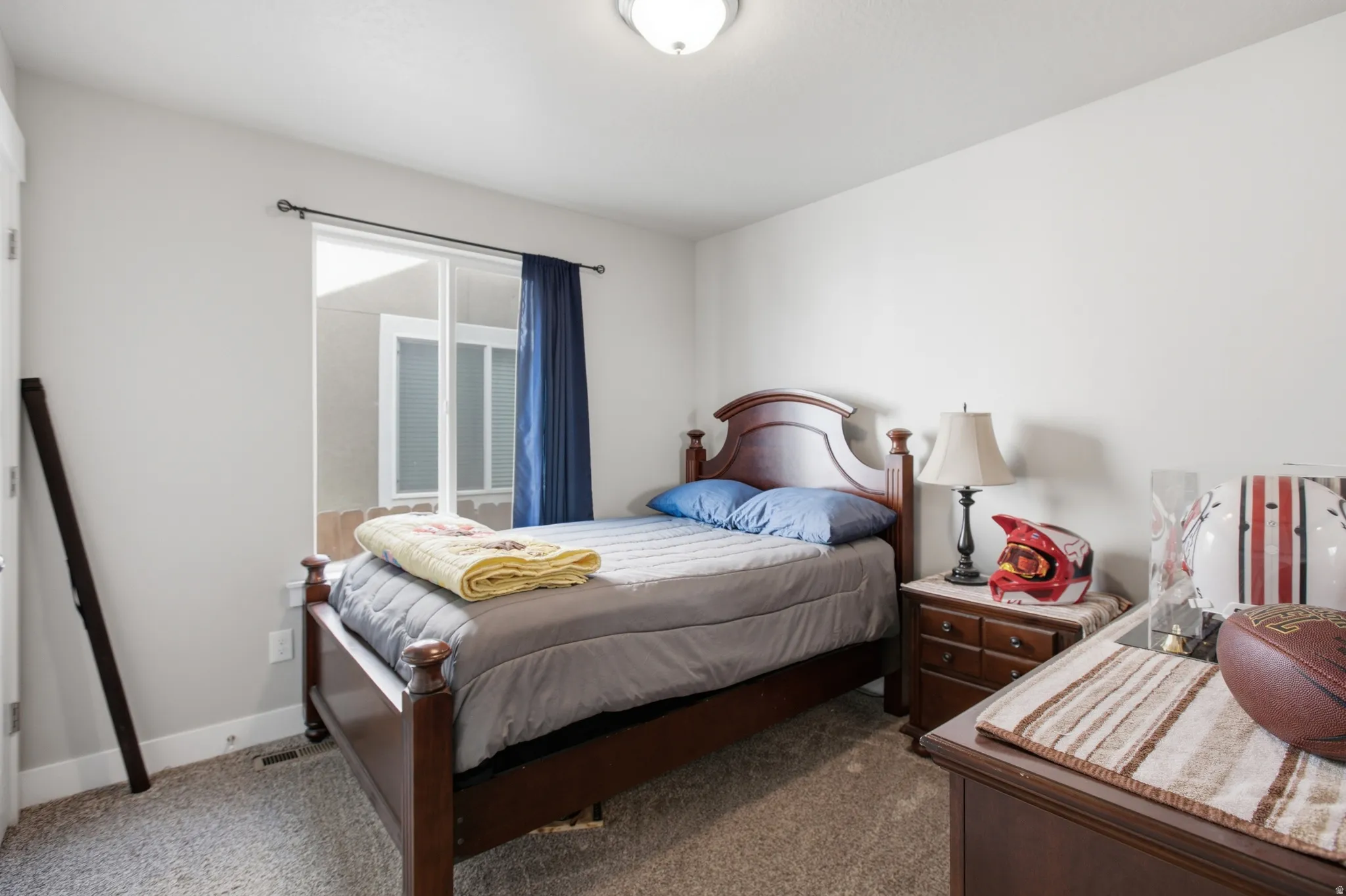 Carpeted bedroom featuring a sliding glass door with exterior courtyard visibility, light neutral wall paint, and a ceiling-mounted light fixture