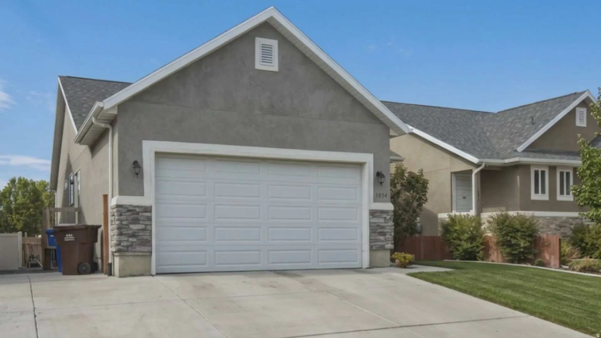 Exterior featuring a two-car garage, stone accent siding, and a stucco finish