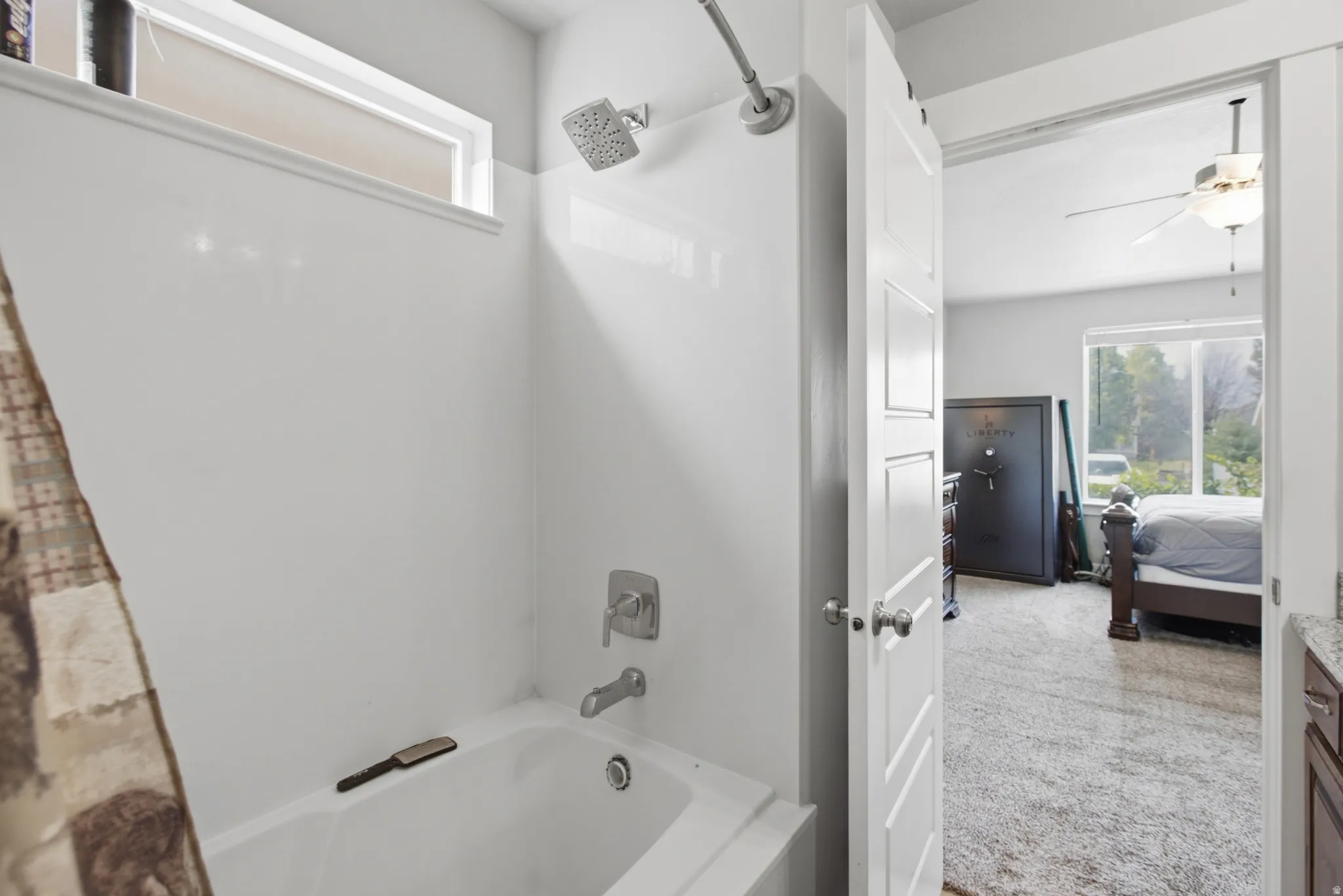 White shower/tub combination with brushed nickel fixtures and an overhead transom window