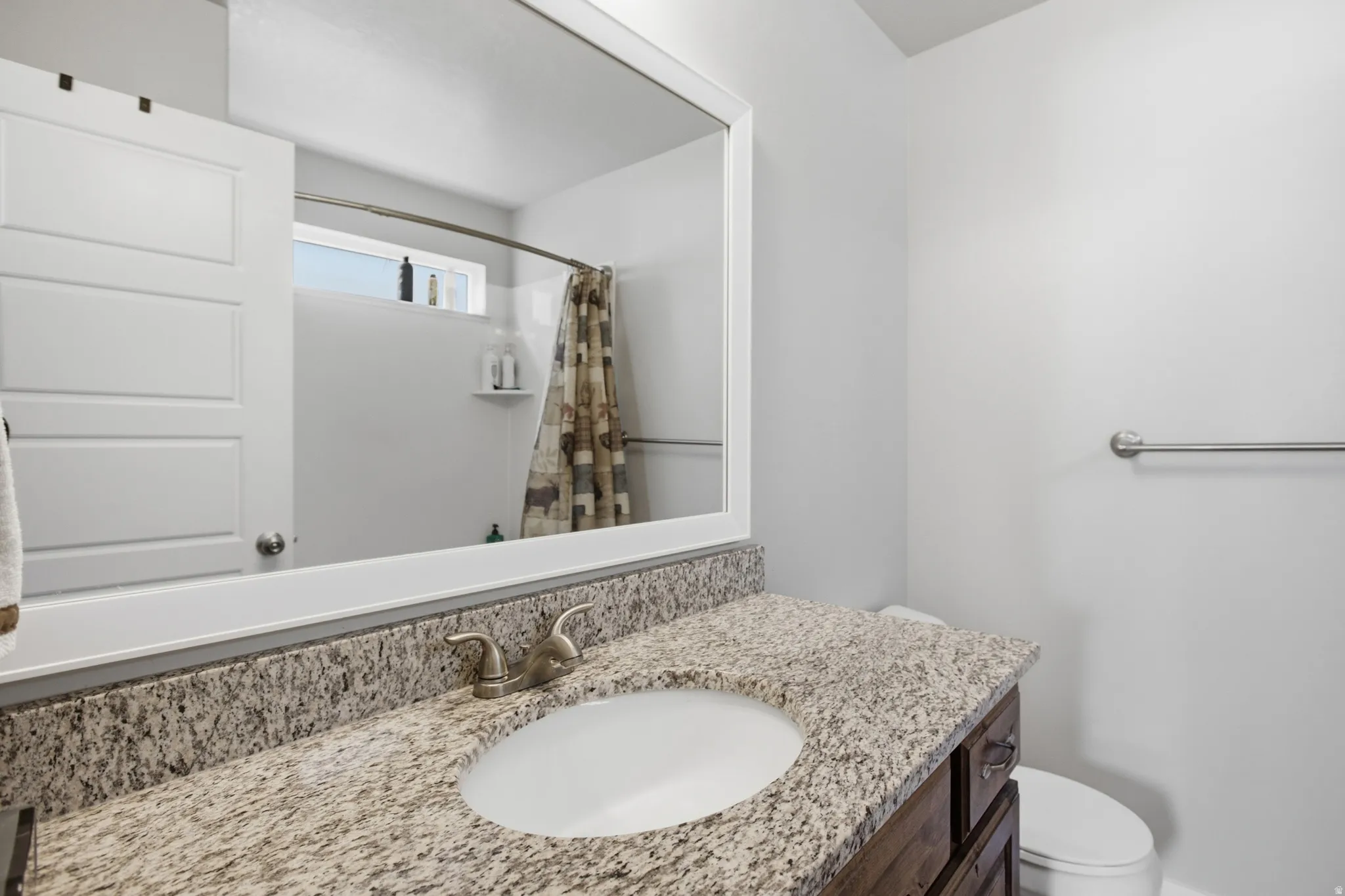Bathroom vanity featuring a speckled countertop, undermount sink, and brushed nickel faucet