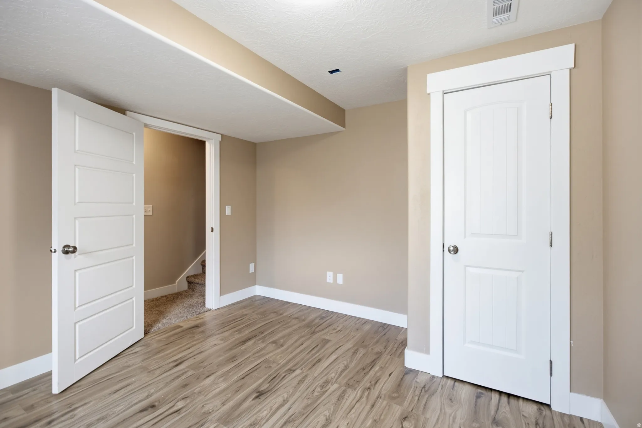Room featuring wood-finish flooring, neutral wall tones, and white trim