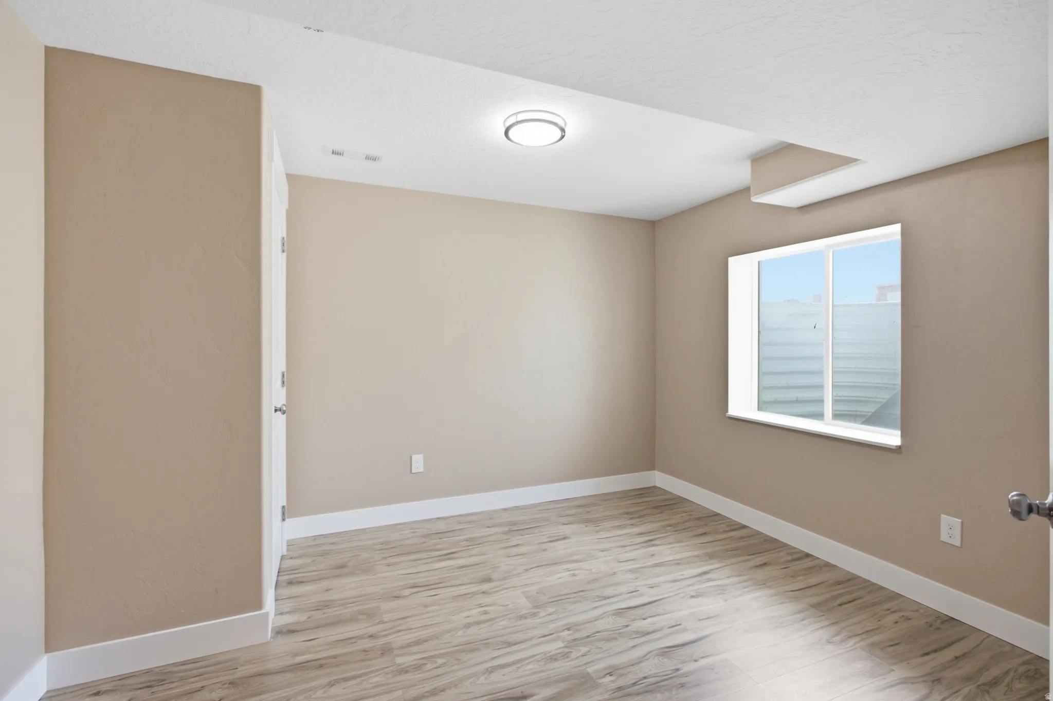 Room featuring wood-finish flooring, neutral wall tones, and white baseboards