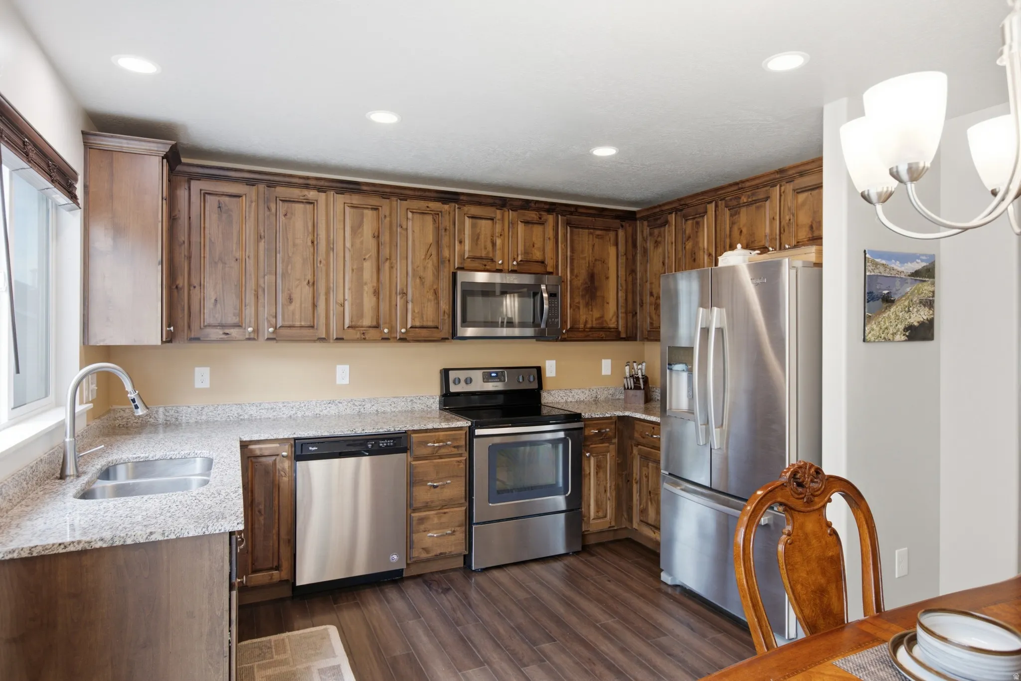 Kitchen featuring wood-finish cabinetry, granite-style countertops, and stainless steel appliances