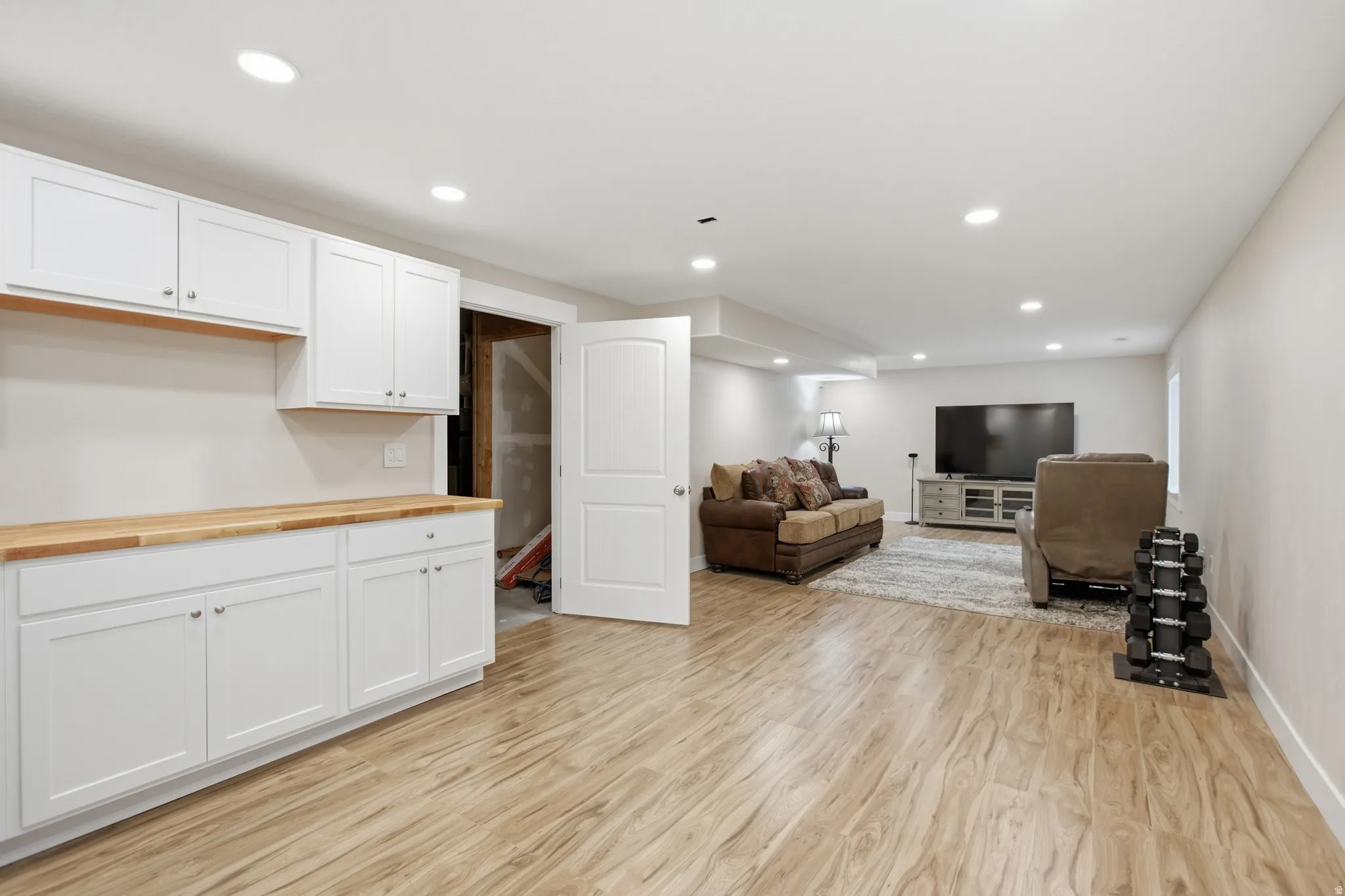 Finished basement space featuring wood-finish flooring, recessed lighting, and white baseboards
