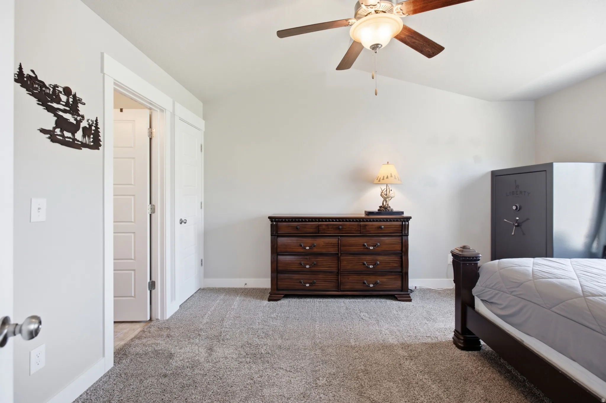 Carpeted interior space featuring a vaulted ceiling with a ceiling fan, light gray walls, and white trim
