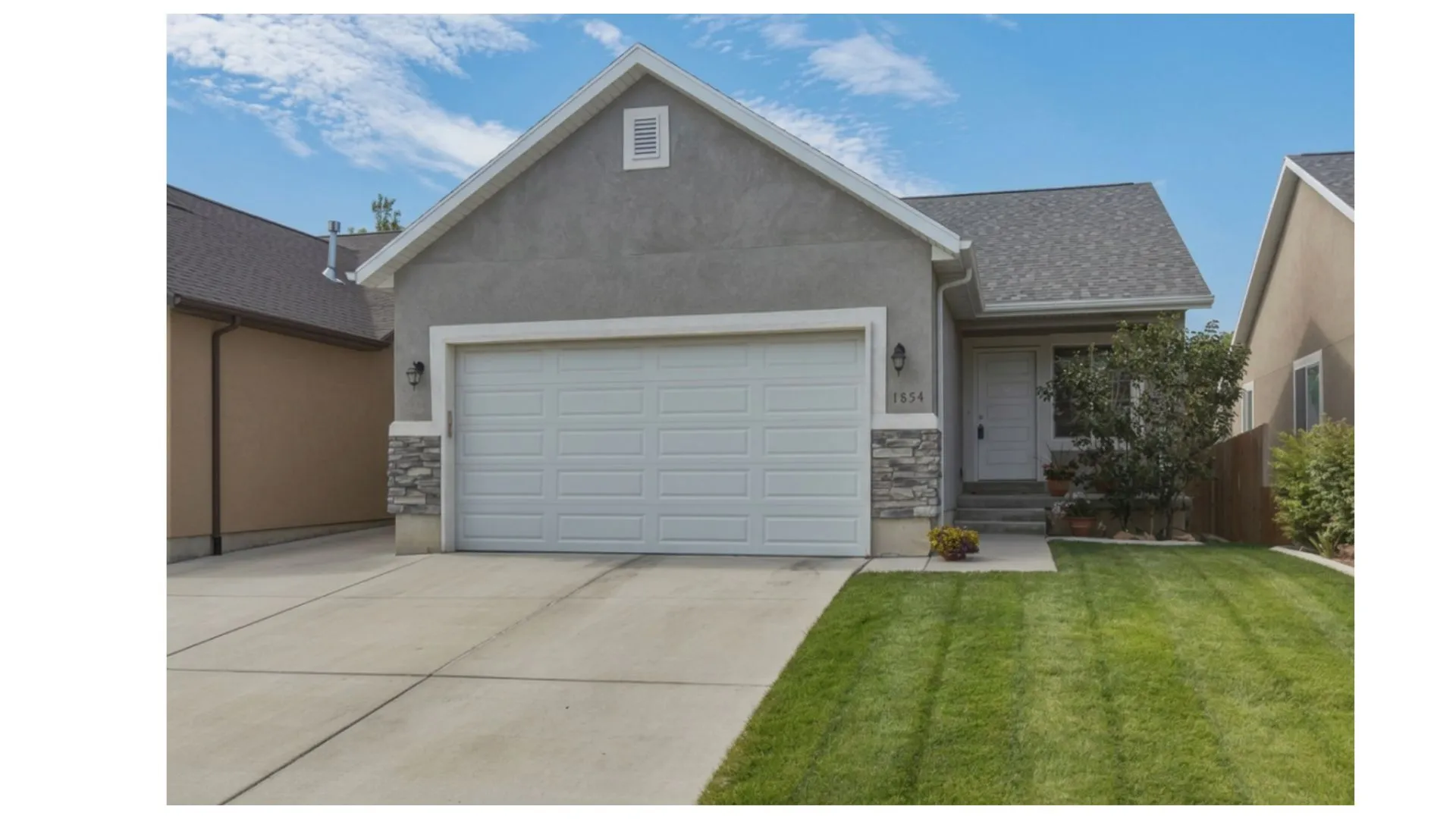 Stucco exterior featuring a two-car garage with a panel door