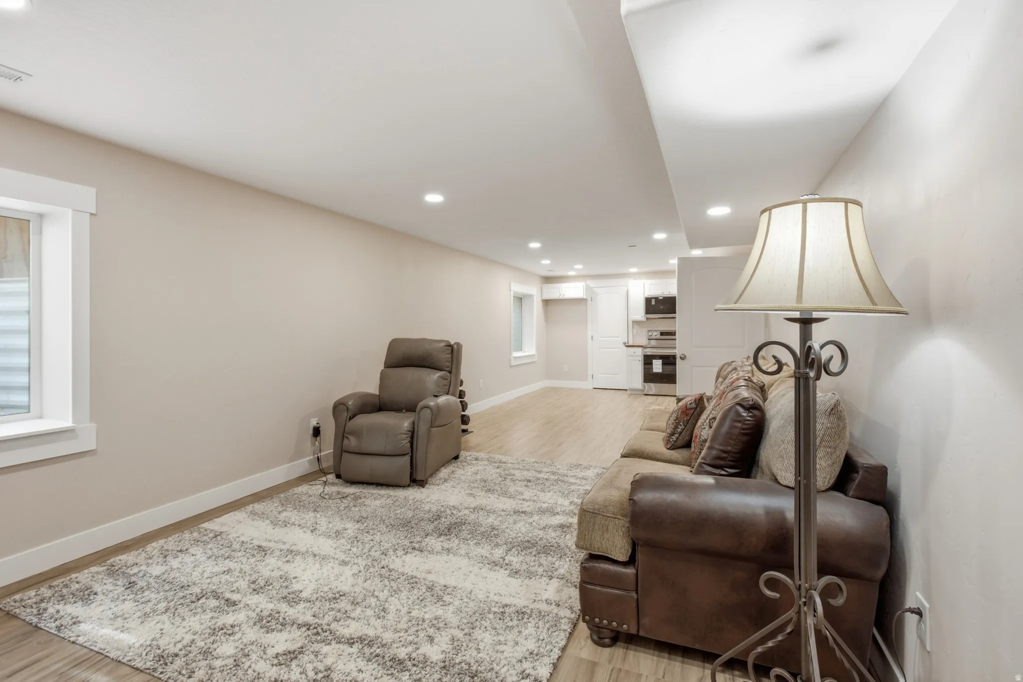 Spacious lower-level living area featuring recessed lighting, light wood-finish flooring, and a window with white trim