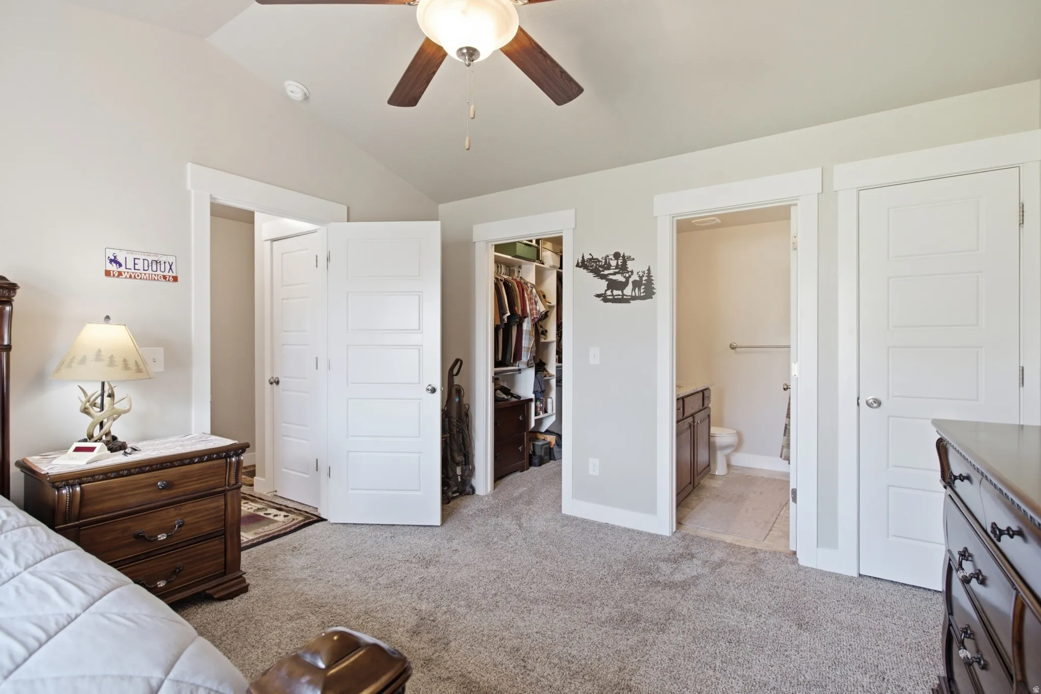 Carpeted bedroom with a vaulted ceiling, ceiling fan, and white trim