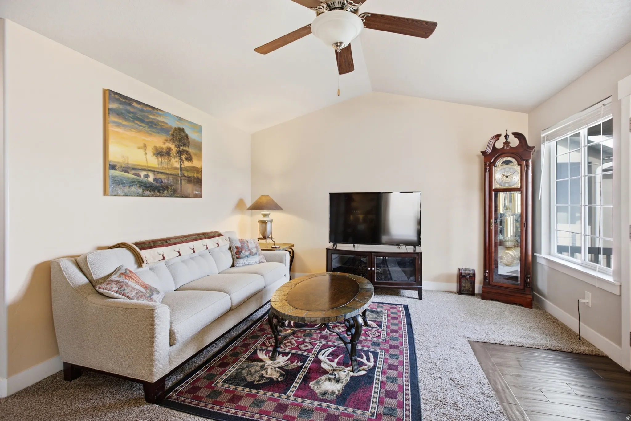 Spacious living area featuring a vaulted ceiling and a ceiling fan with integrated lighting