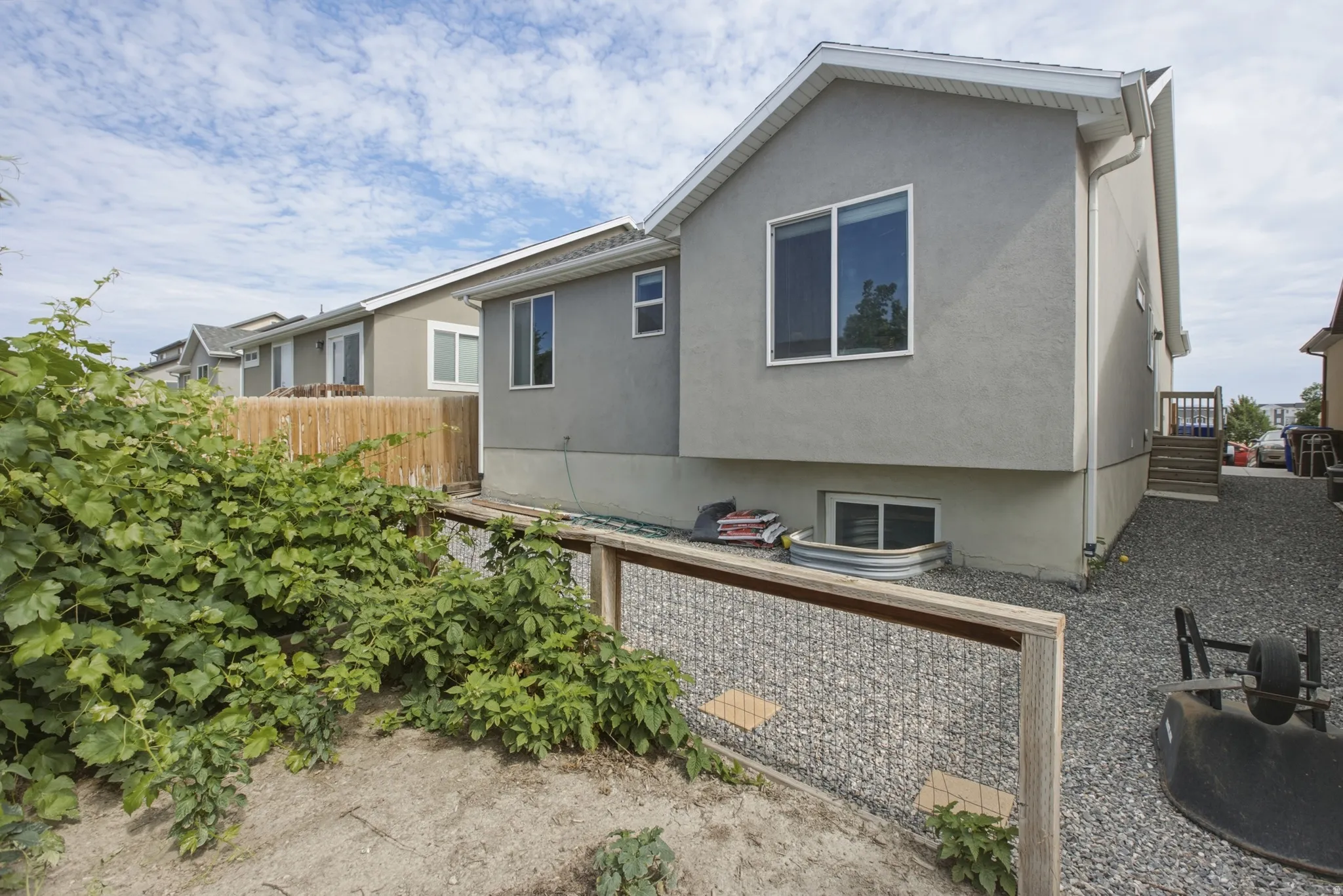 Stucco exterior featuring multiple windows and a wood fence