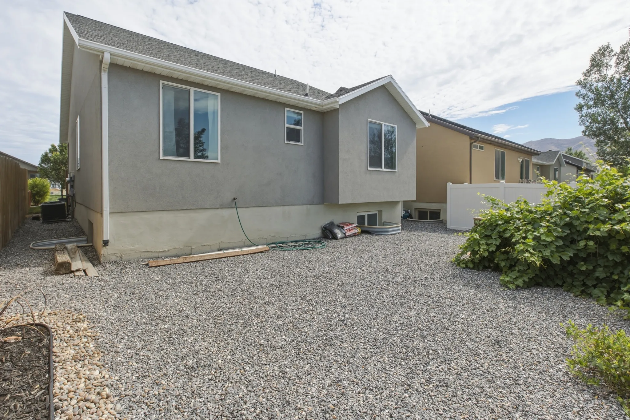 Exterior featuring a stucco finish, multiple windows, and a gravel yard