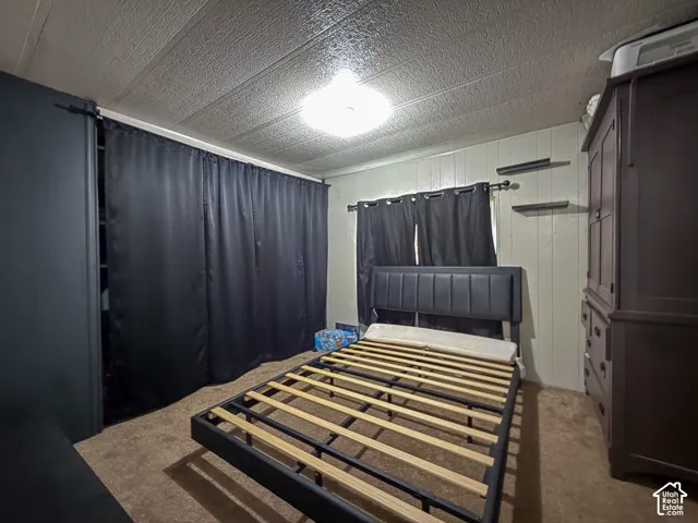 Bedroom featuring tan carpeting and paneled walls