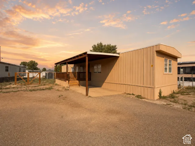 Property featuring a covered wooden deck, light-colored siding, and a gravel lot