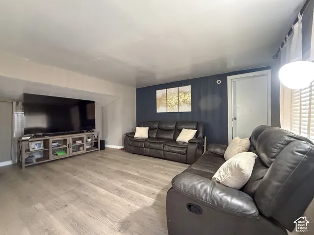 Open living area featuring wood-finish flooring, a contemporary accent wall, and recessed lighting