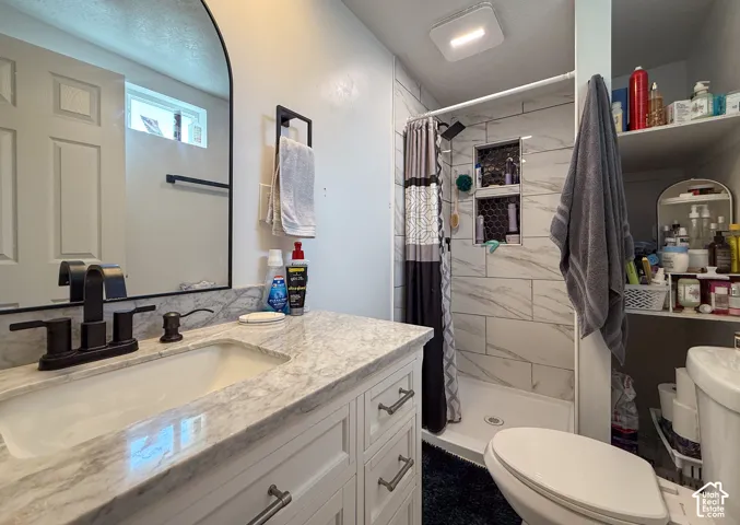 Bathroom featuring a white vanity with a stone-finish countertop and integrated sink, a dark bronze-finish faucet, and an arched mirror