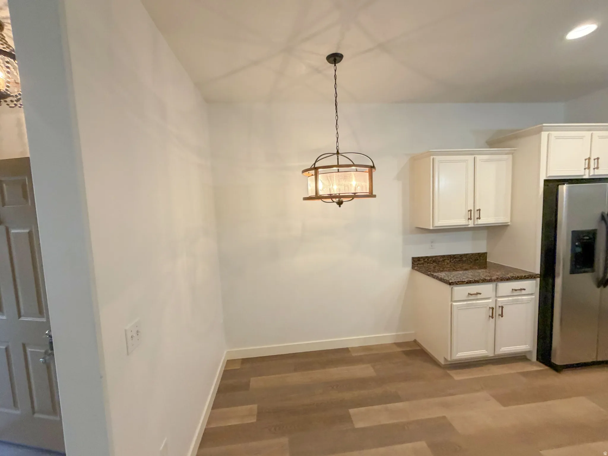 Dining area featuring a decorative ceiling pendant light, wood-finish flooring, and crisp white walls