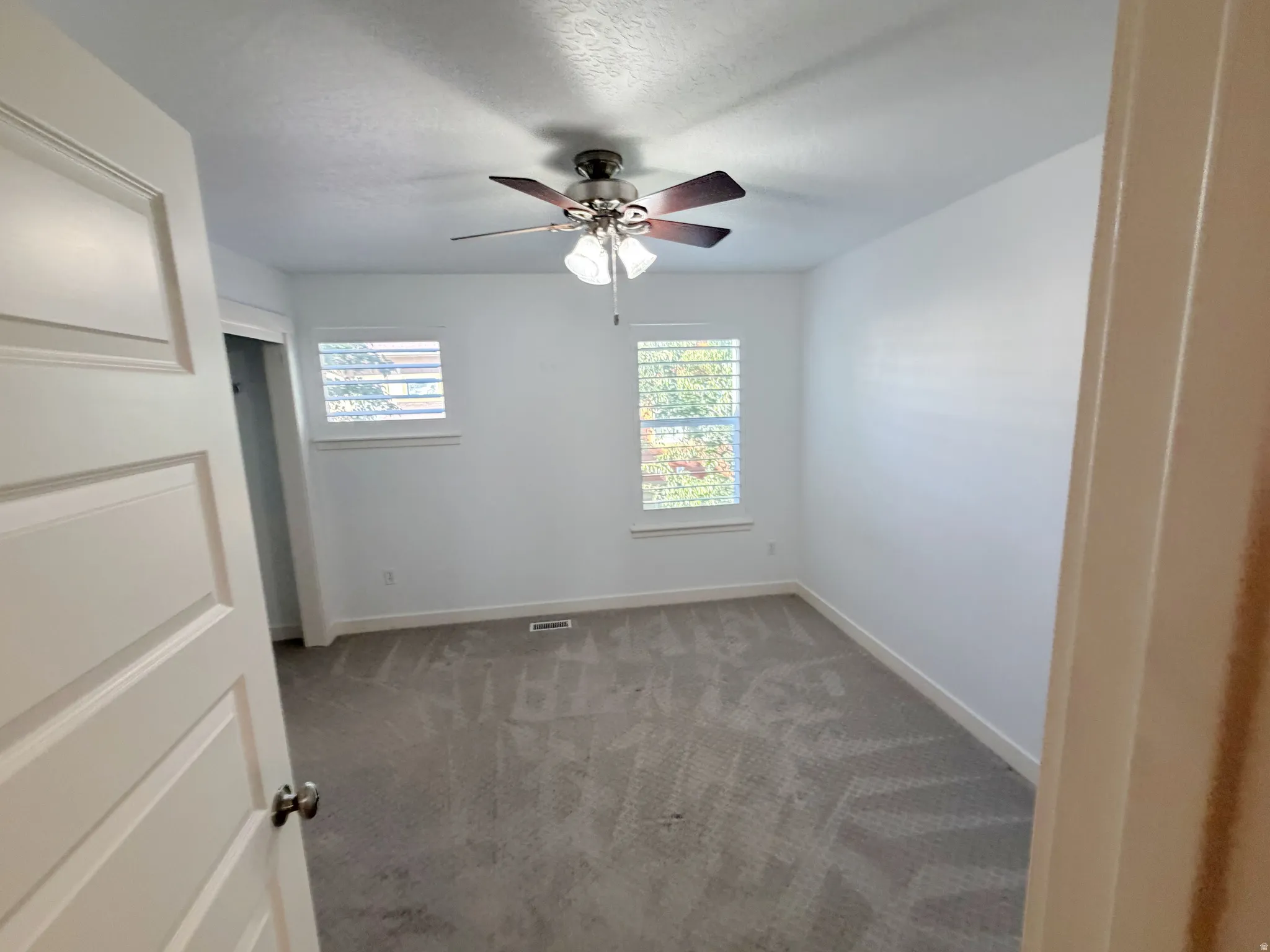 Room featuring neutral-toned carpeting, white walls, and a ceiling fan with integrated lighting