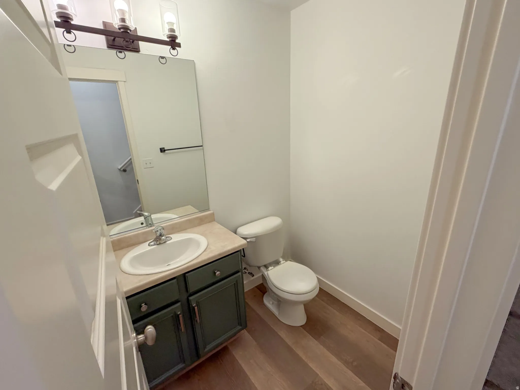 Vanity with an integrated white sink, beige countertop, and dark green cabinetry