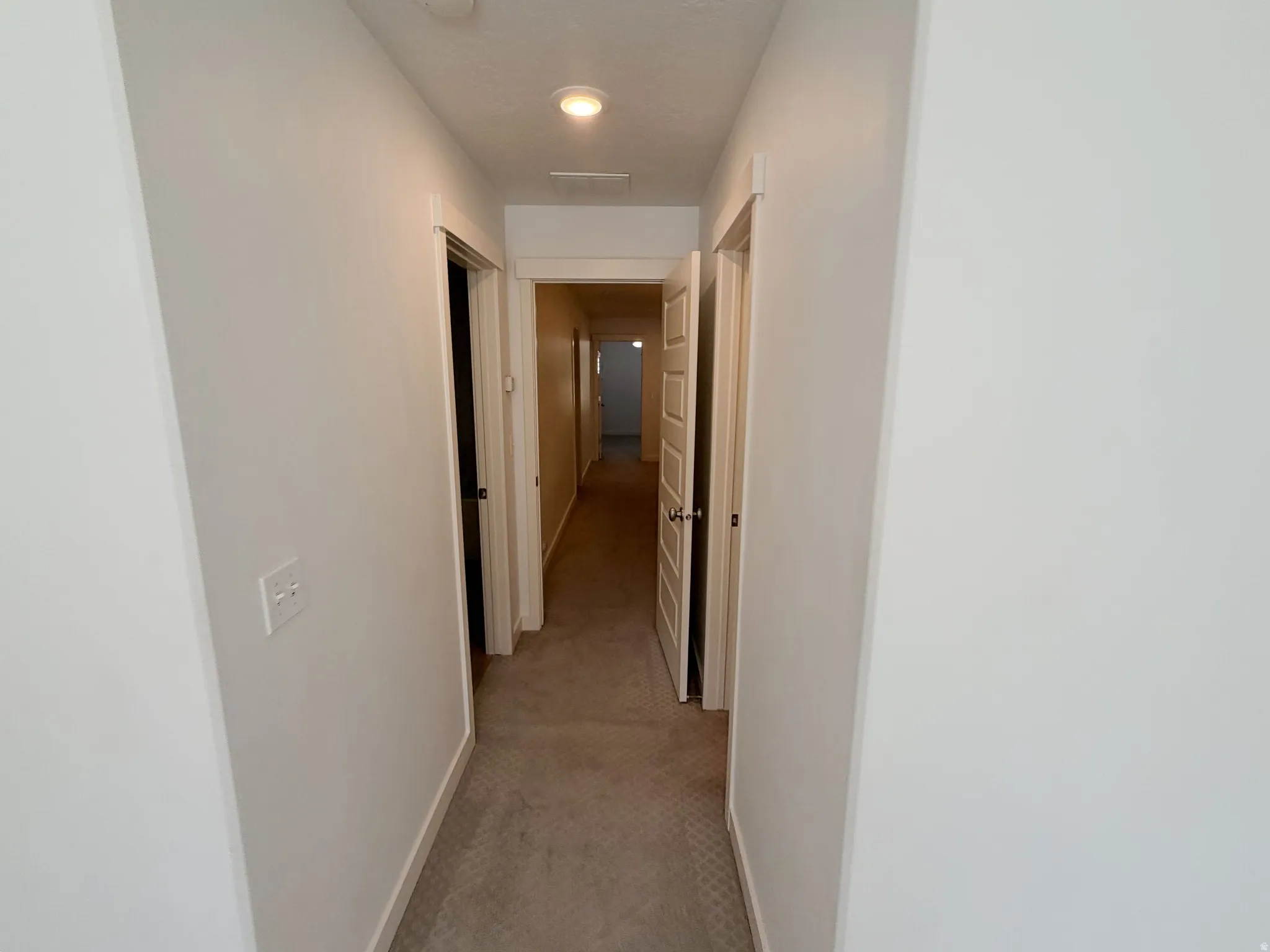 Hallway featuring neutral-toned carpet, white painted walls, and recessed lighting fixtures