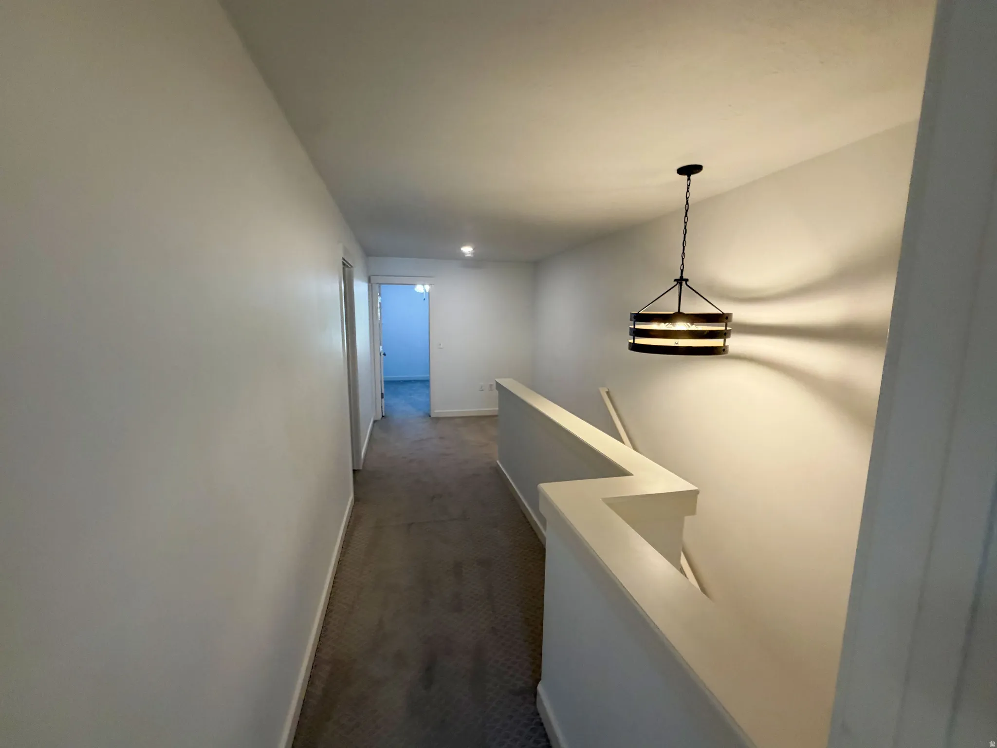 Upper-level hallway featuring a contemporary drum pendant light fixture, light gray carpeting, and white painted walls