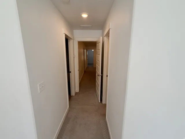 Hallway featuring neutral-toned carpet, white painted walls, and recessed lighting fixtures