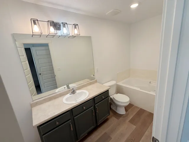 Contemporary bathroom featuring a single vanity with dark cabinetry, integrated sink, and a light-toned countertop