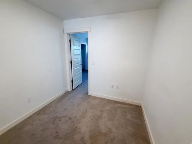 Carpeted room featuring white walls and baseboards