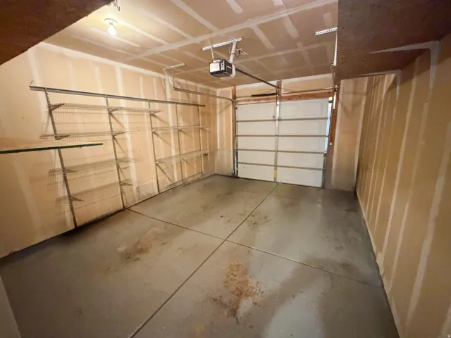 Attached garage with a white sectional door, concrete flooring, and an overhead lighting fixture