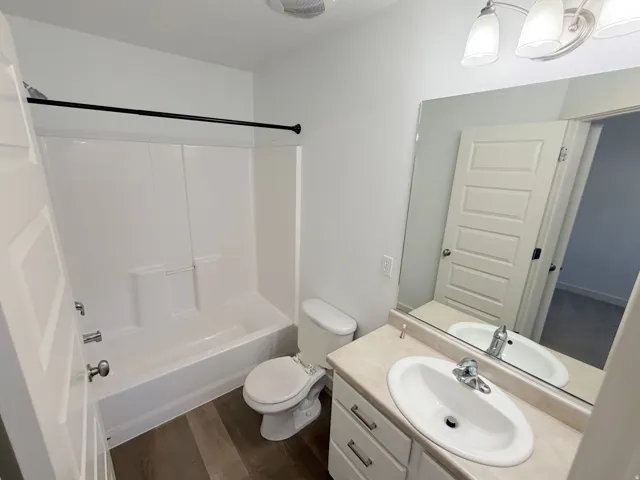 Bathroom featuring a white vanity with an integrated sink, a rectangular mirror, and a two-light fixture