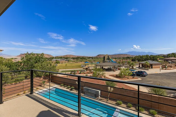 Patio with a metal railing overlooking a swimming pool, desert landscaping, and distant mountains