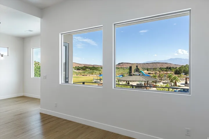 Bright interior with white walls and wood-finish flooring, featuring large windows with clear views of the distant mountains and nearby green spaces