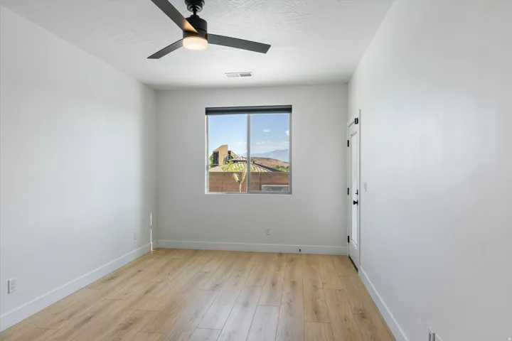 Bright interior space featuring wood-finish flooring, a window offering distant mountain scenery, and a modern ceiling fan with integrated lighting