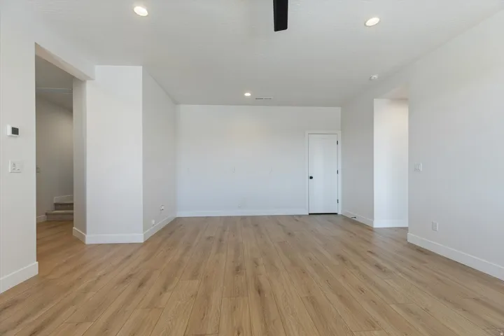 Spacious room featuring wood-finish flooring, recessed lighting, and a neutral color palette