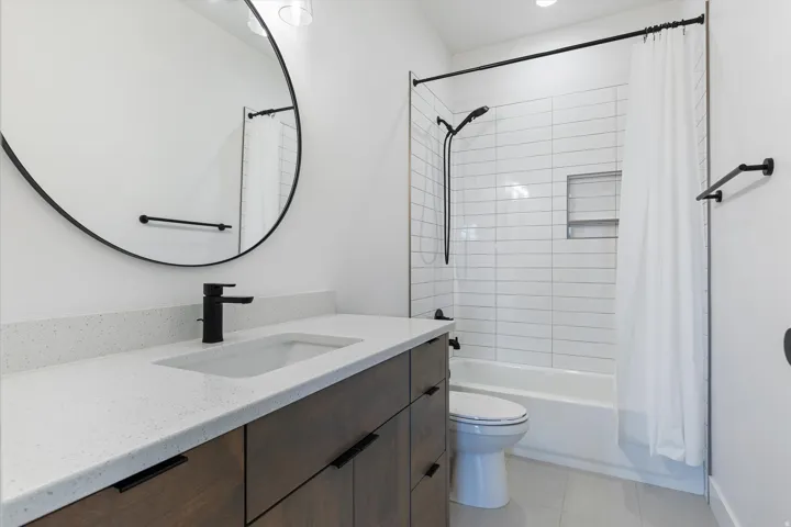 Modern bathroom featuring a wood-finish vanity with a light speckled countertop, an undermount sink, and a matte black faucet