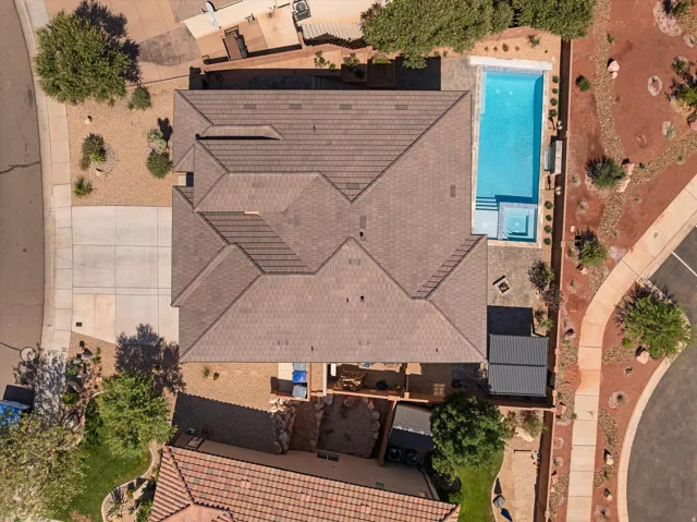 Shingle roof residence featuring a rectangular swimming pool with integrated spa, concrete patio, and an attached covered outdoor structure