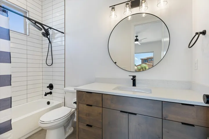 Bathroom featuring a wood-finish vanity with a light-toned countertop and an integrated rectangular sink