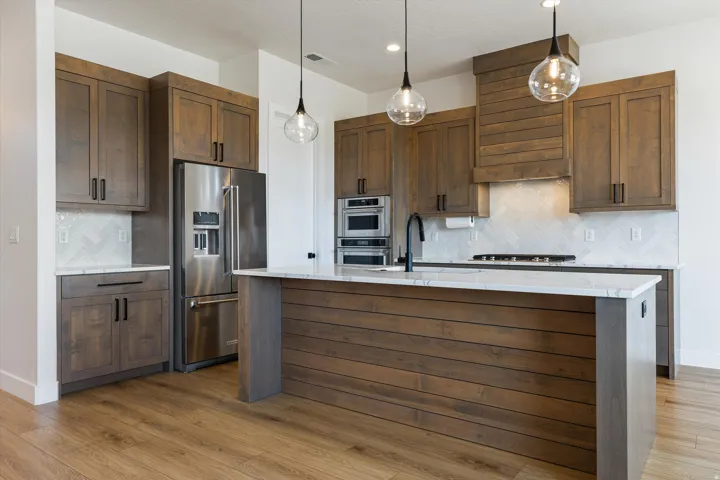 Kitchen featuring a wood-panel island with a white countertop, recessed lighting, and three glass pendant lights