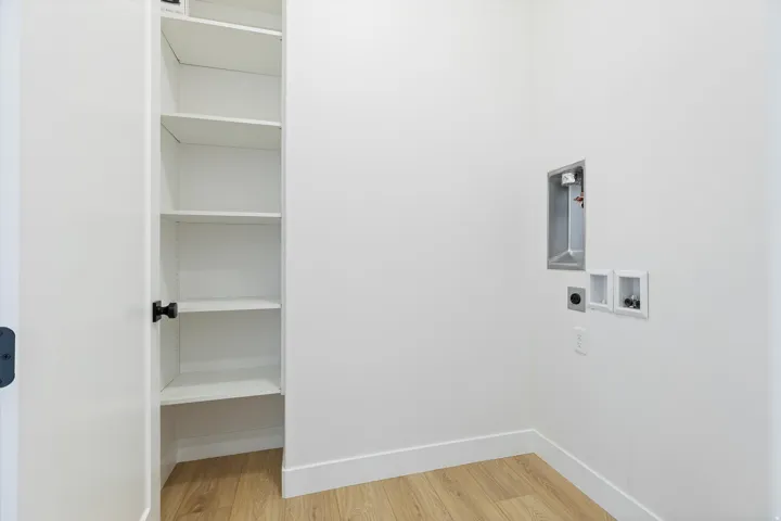 Dedicated utility area featuring wood-finish flooring, white walls, and built-in shelving
