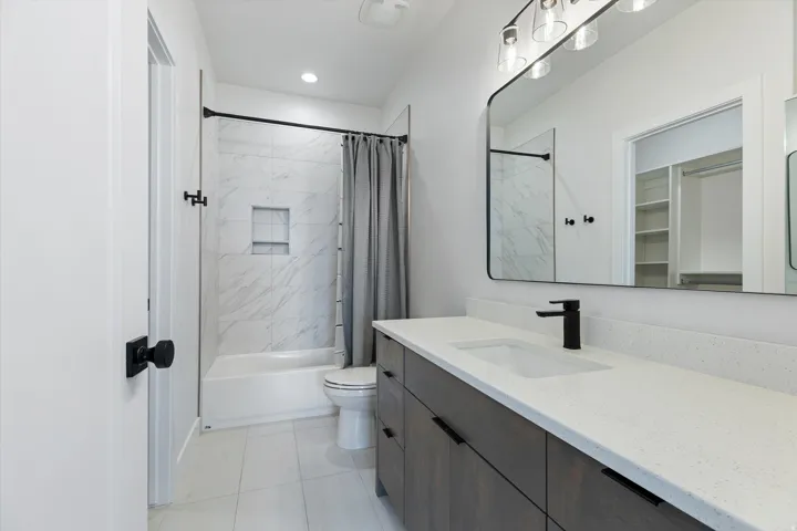 Bathroom featuring a single vanity with dark wood-finish cabinetry, a white countertop, and a black matte faucet