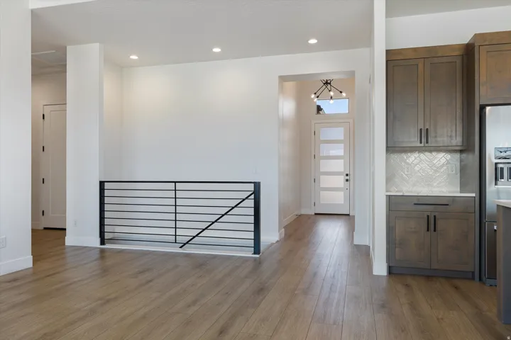 Modern interior featuring wood-finish flooring, recessed lighting, and a contemporary black metal railing
