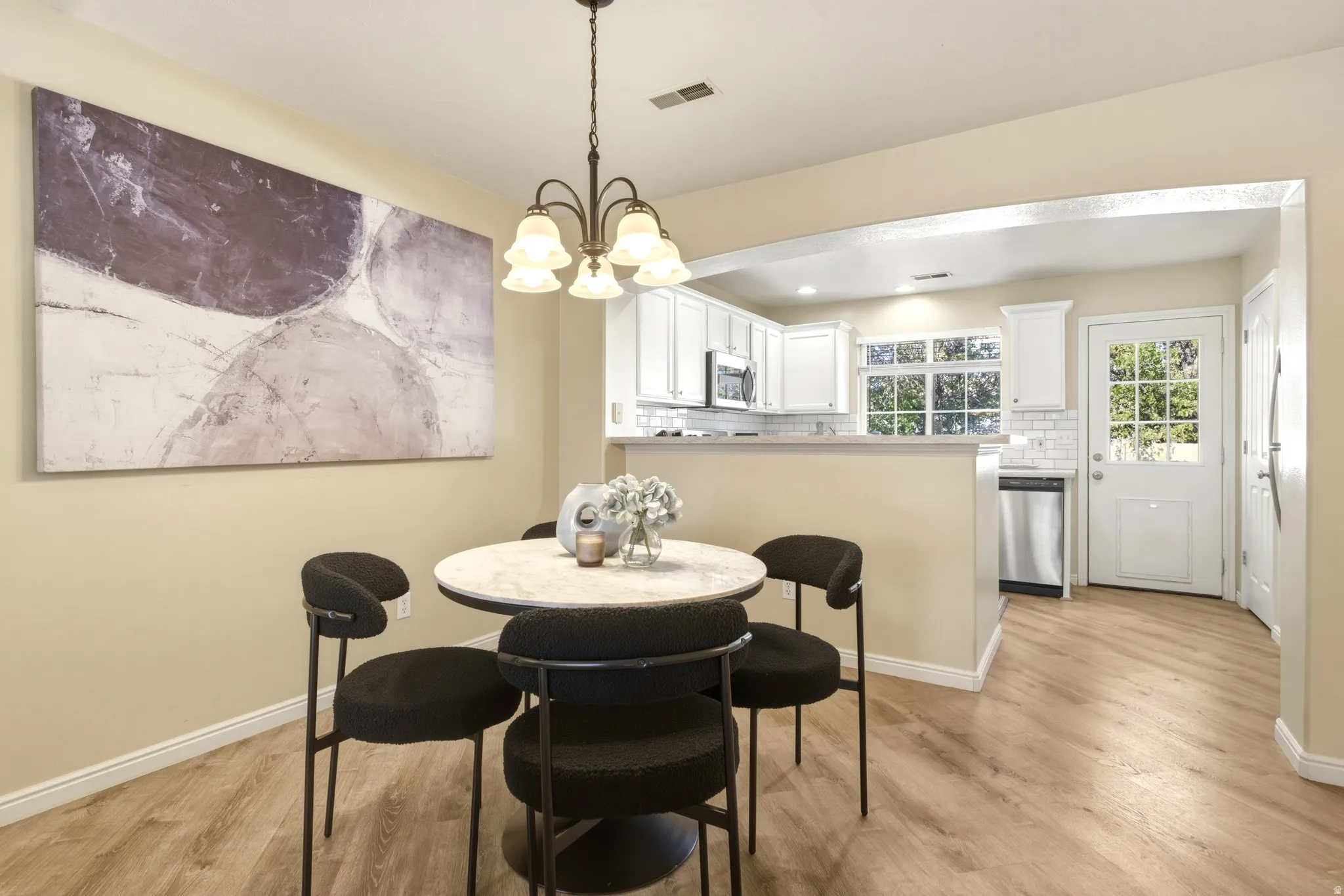 Dining area featuring a central chandelier, wood-finish flooring, and an arched entryway to the kitchen