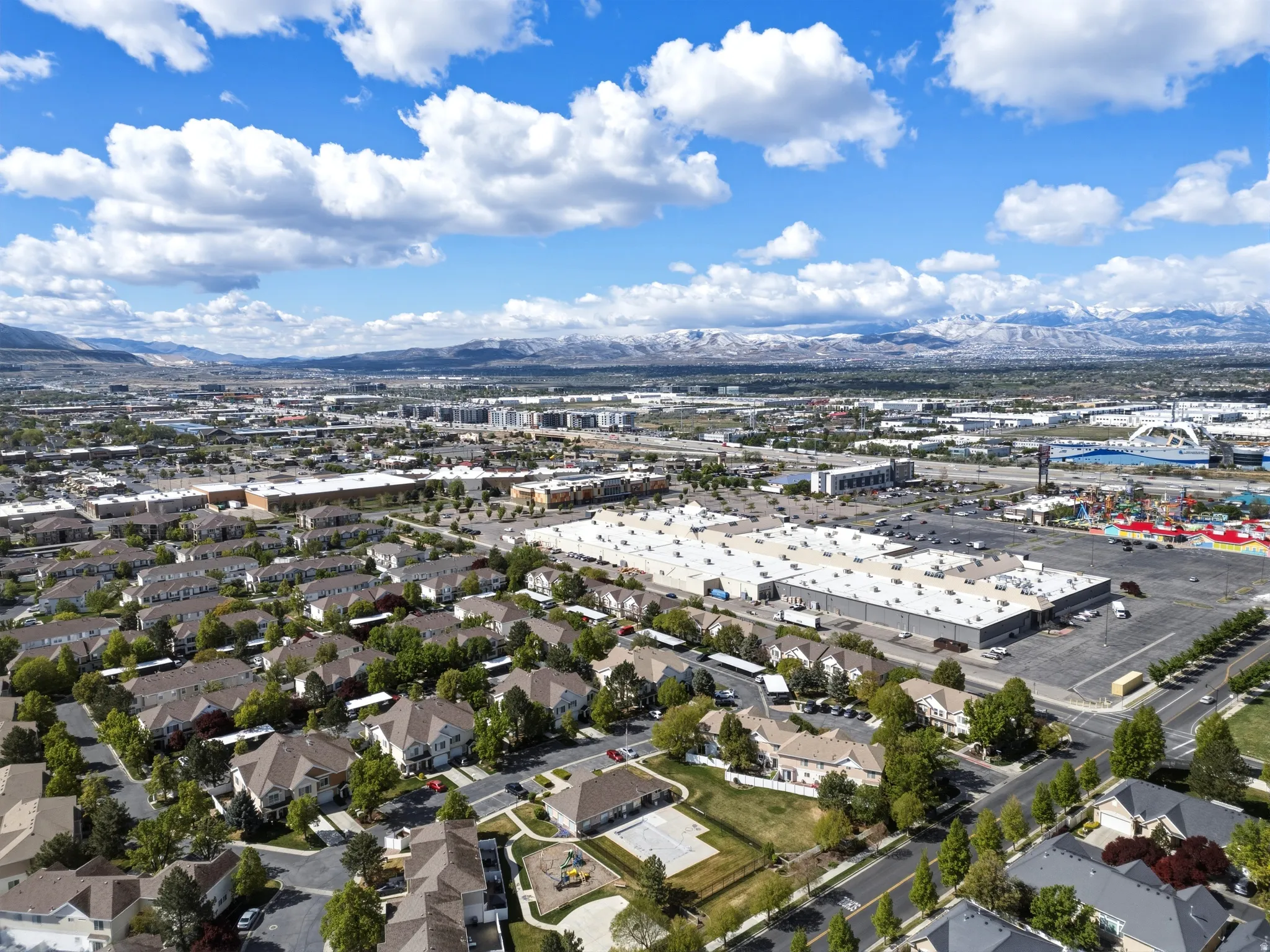 Aerial perspective showcasing a residential community with varied architectural styles, mature landscaping, and an adjacent commercial district