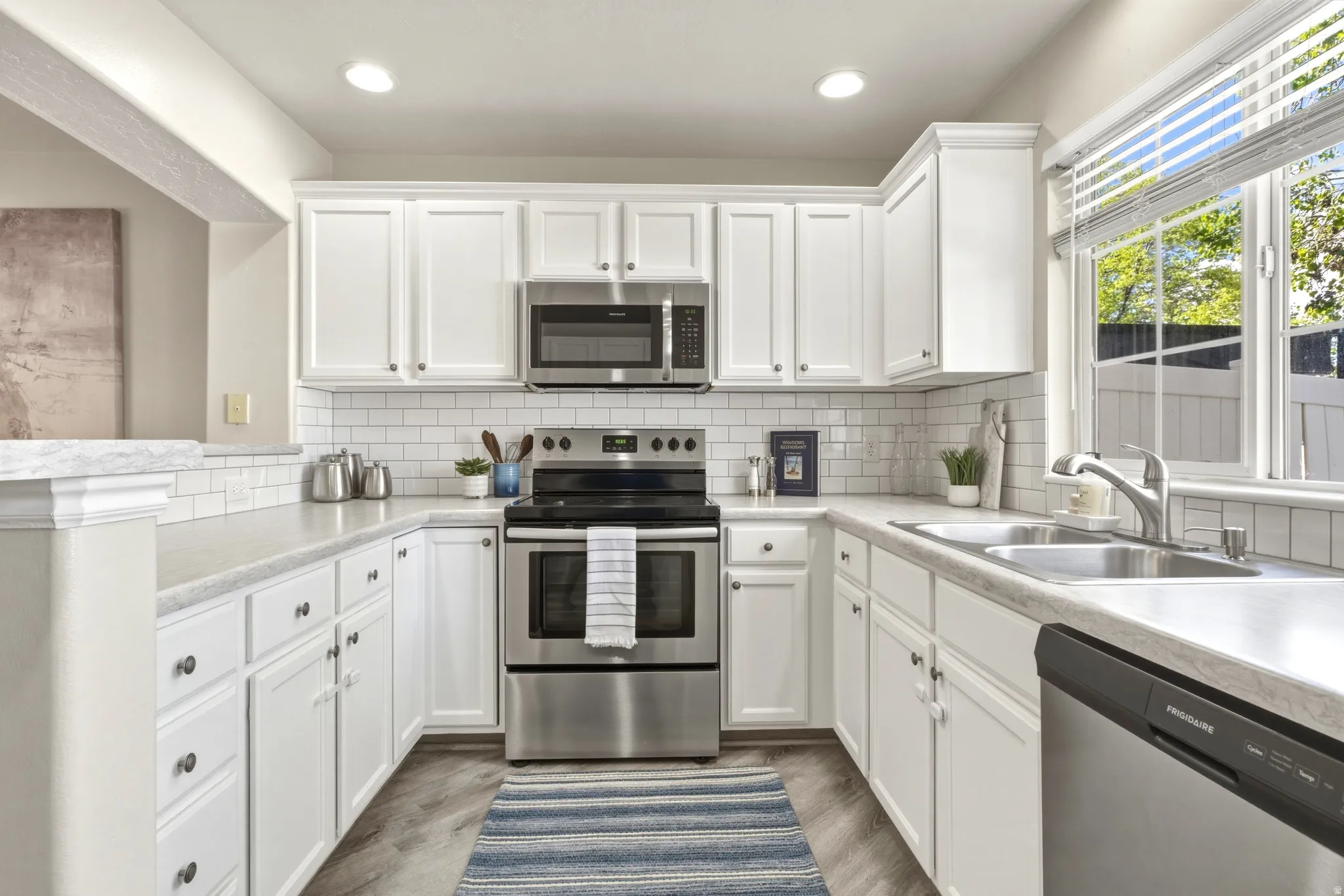 Kitchen featuring white shaker-style cabinetry, subway tile backsplash, and stainless steel appliances