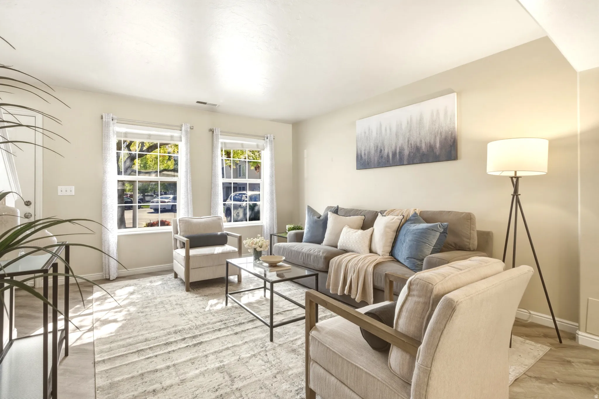 Spacious living area featuring light-toned wall paint and wood-finish flooring