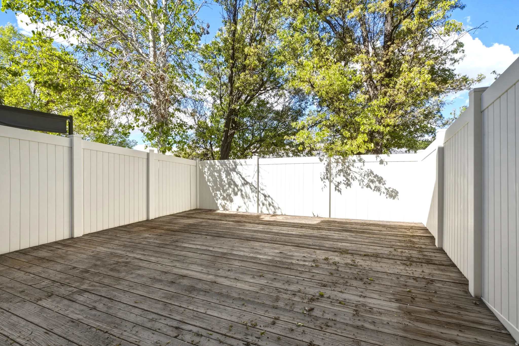 Expansive outdoor deck featuring wood-finish flooring and full privacy fencing