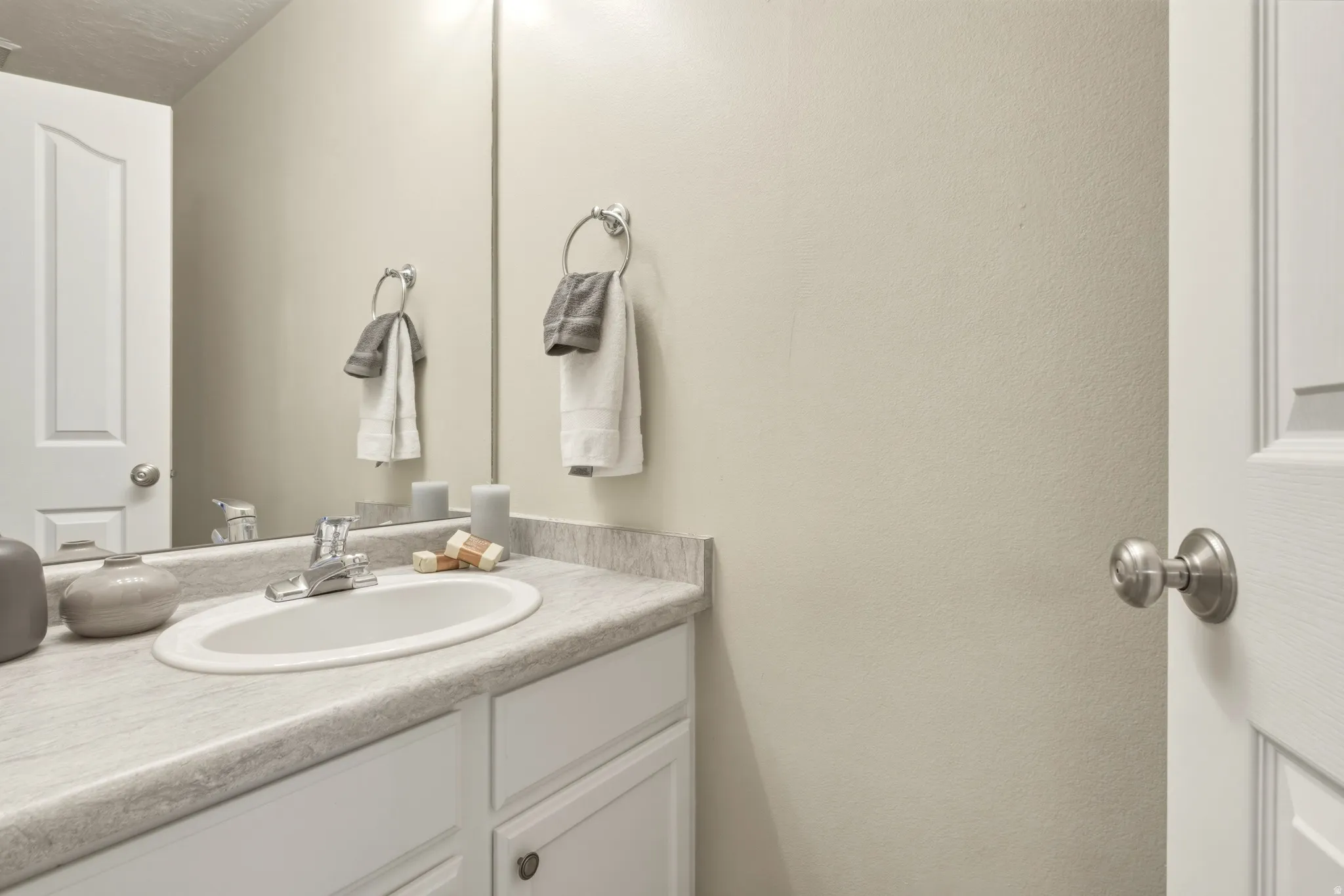 White vanity with an integrated oval sink, chrome faucet, and grey-toned countertop