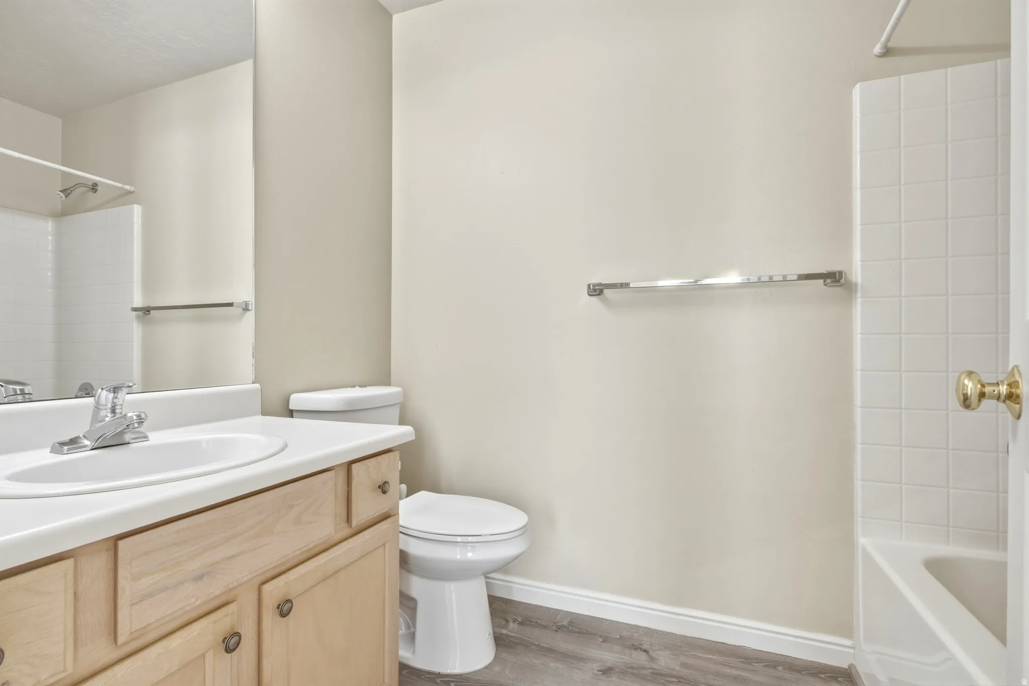 Bathroom featuring a single vanity with a laminate countertop, light wood-finish cabinetry, and a chrome faucet