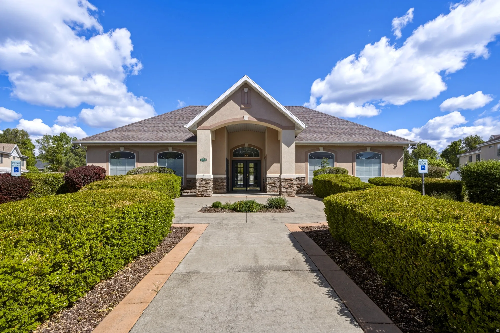 Stucco exterior building featuring a covered entryway with stone veneer accents