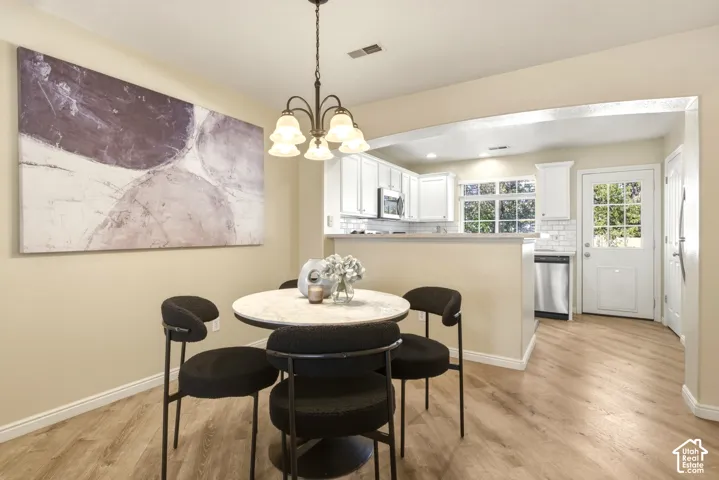 Dining area featuring a central chandelier, wood-finish flooring, and an arched entryway to the kitchen