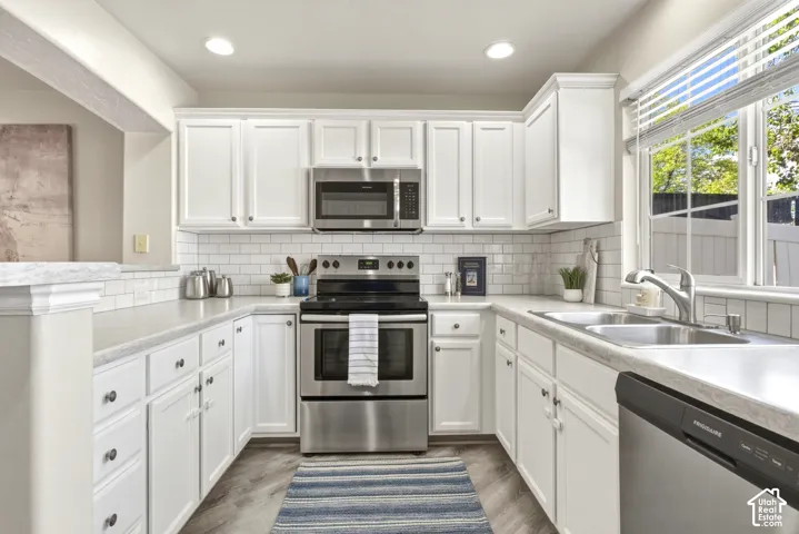 Kitchen featuring white shaker-style cabinetry, subway tile backsplash, and stainless steel appliances